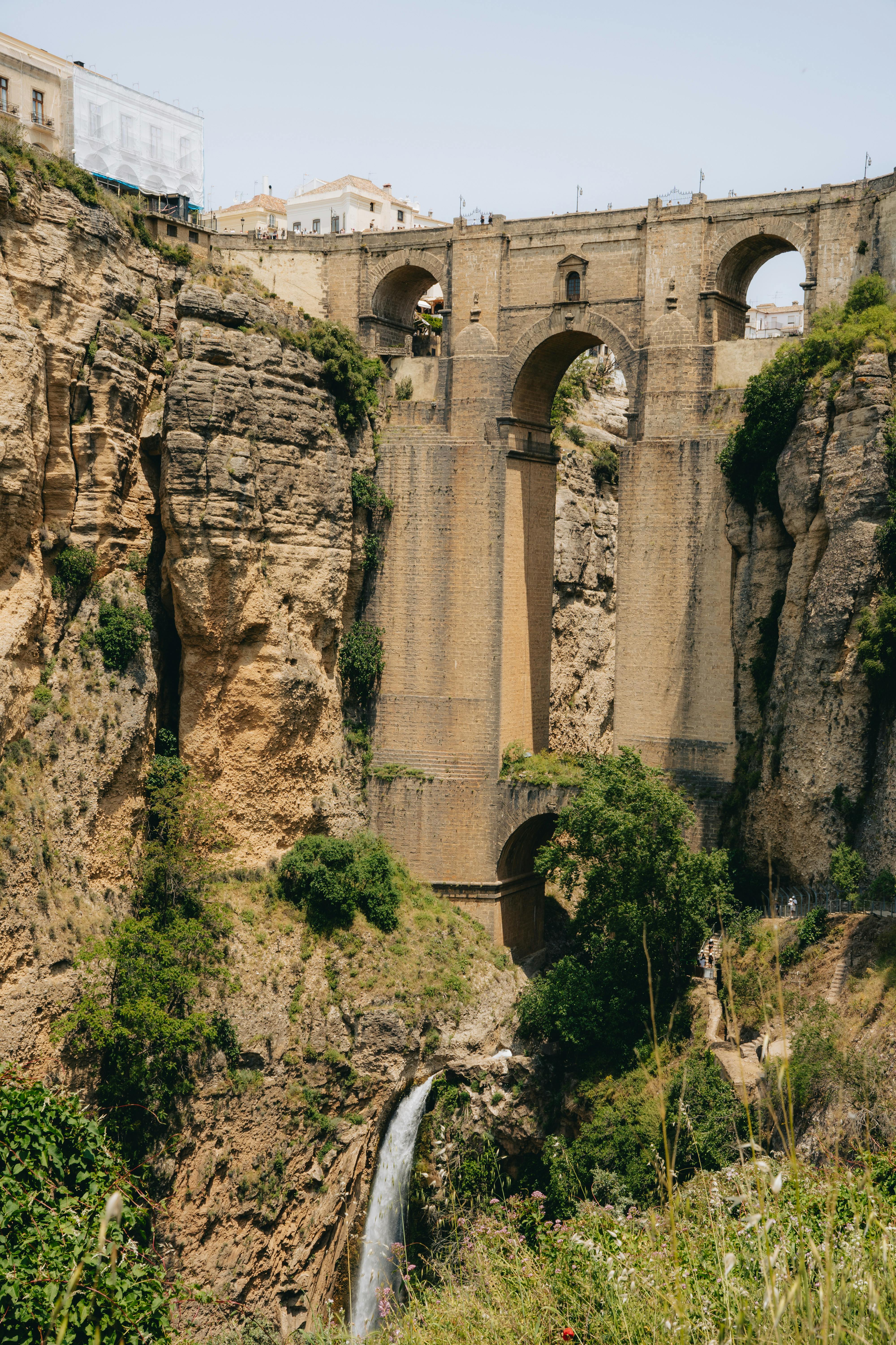 A historic stone bridge in Andalusia under a warm sunlit sky — typical of the regional architecture that anchors small-town walking stays.