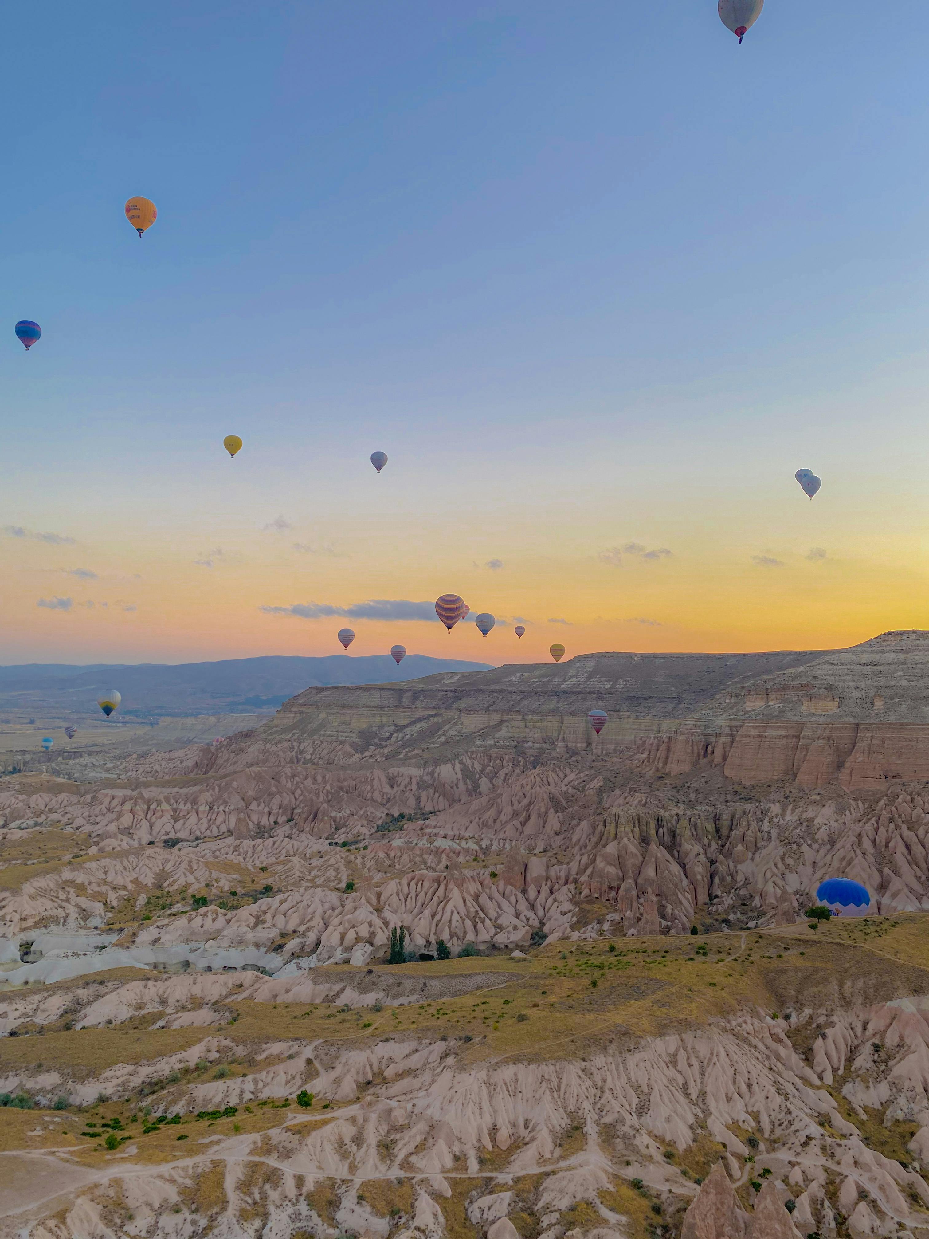 Hot air balloons rising at sunrise over Cappadocia's fairy chimneys — the geological-aerial signature that defines the region's slow-travel calendar.