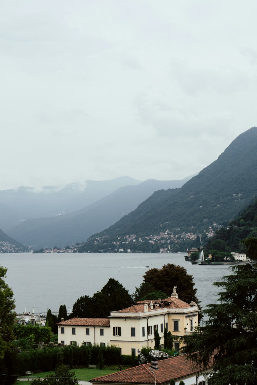 Lake Como with the foothills of the Alps and a lakefront village — the topography that makes a Cernobbio vs. Bellagio vs. Tremezzo base decisive.