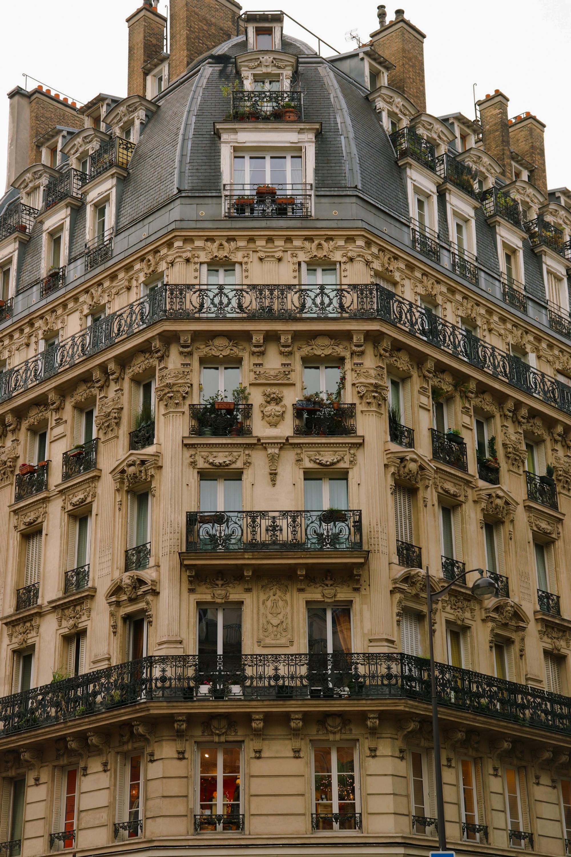 A Haussmann-era apartment building in Paris with ornate iron balconies and a mansard roof — the architectural language most Paris aparthotels inhabit.